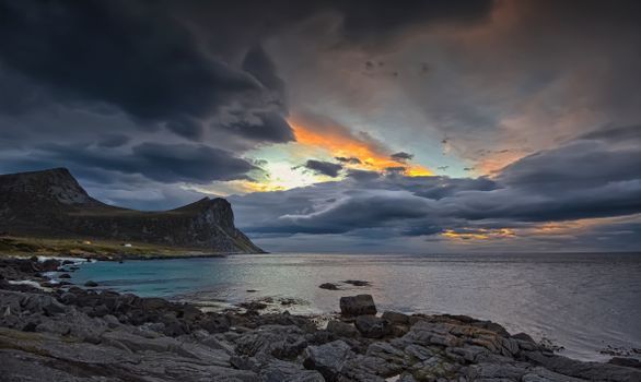Vivid twilight over dramatic Lofoten coastline with rocky shore and colorful sky.