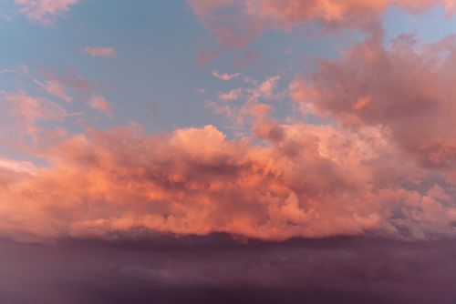 Free Stunning sunset cloudscape featuring vivid pink and orange clouds against a blue sky. Stock Photo