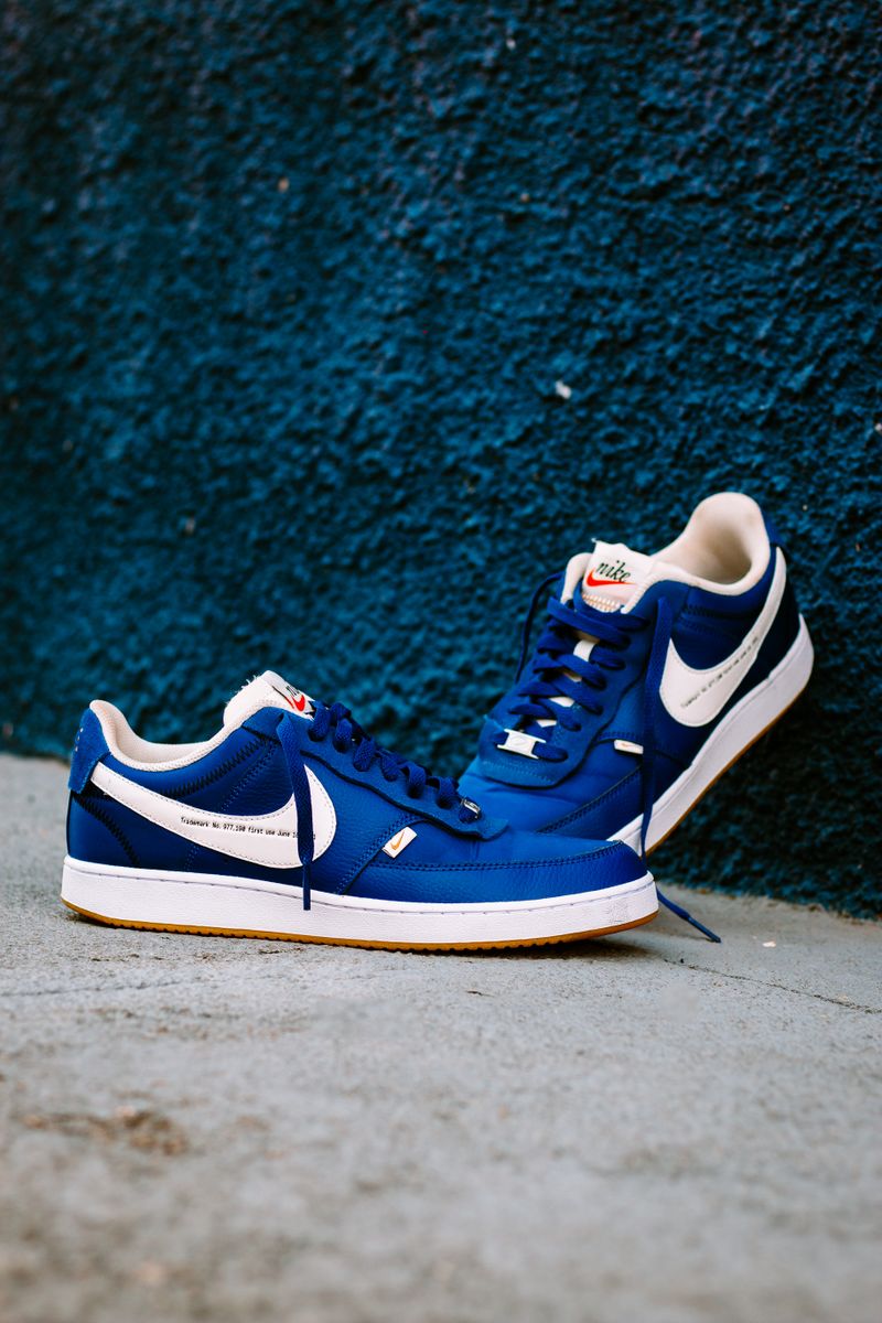 Zapatilla azul cobalto con detalle blanco frente a una pared azul