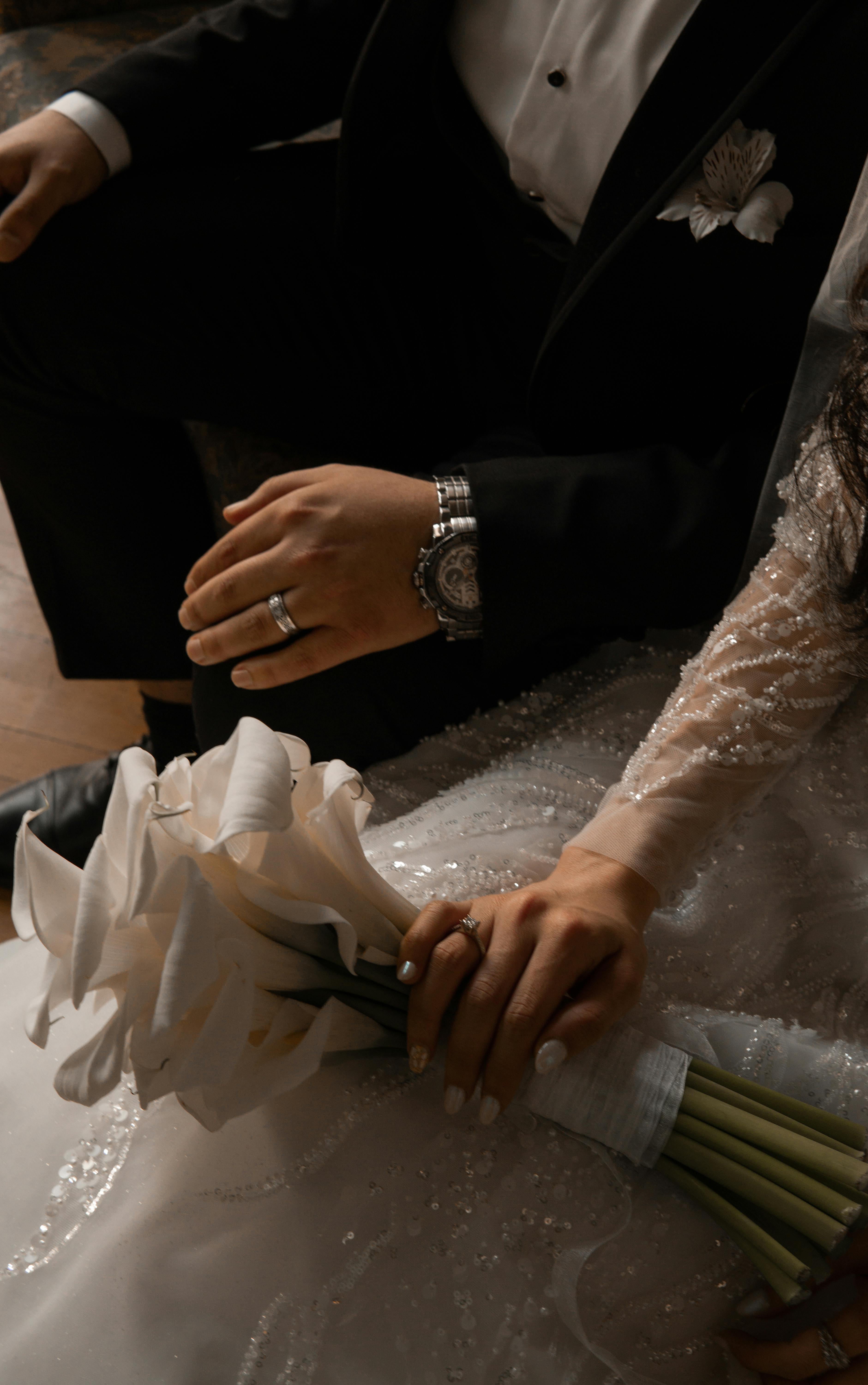 Close-up of elegant couple's hands with rings and bouquet at a wedding in Baku, Azerbaijan.