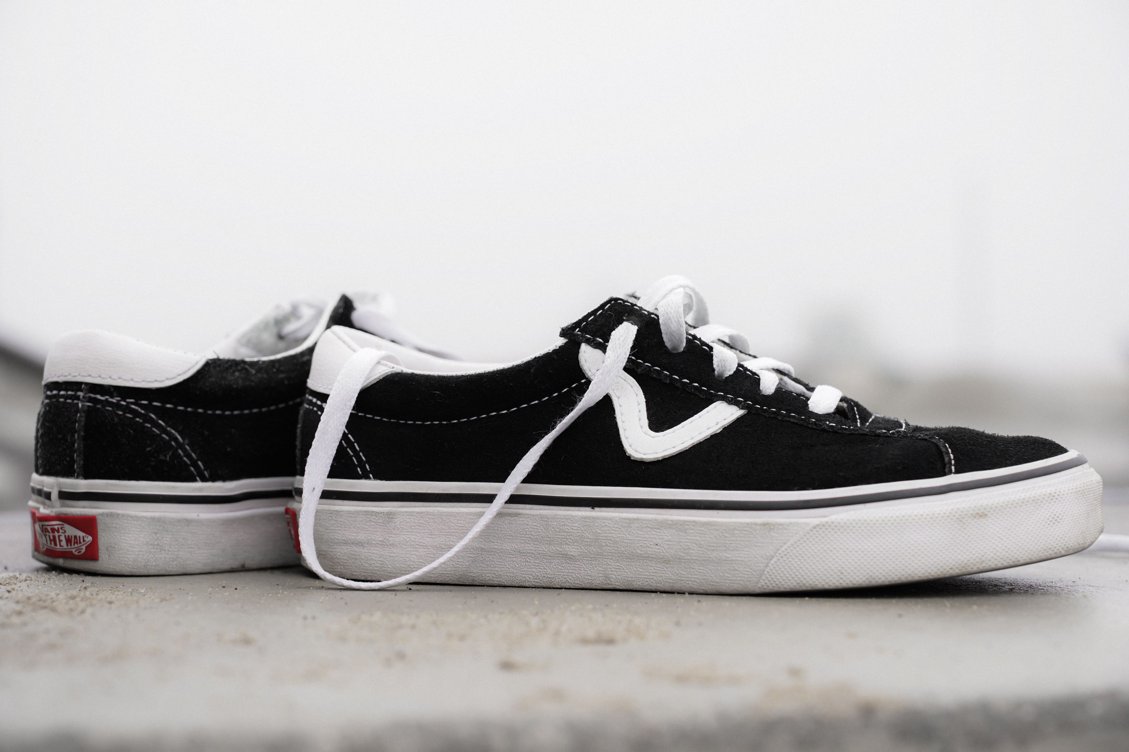 Close-up of stylish black and white skate shoes with visible laces on a concrete surface.