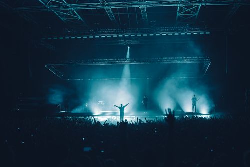 Free Energetic concert scene with a silhouetted performer and vibrant audience lighting. Stock Photo