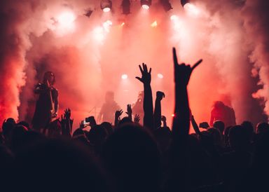 A festival crowd lit red by the stage rig