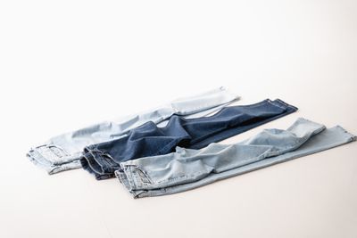 Three pairs of blue jeans on a white ground, photo by Dmitriy Steinke on Pexels