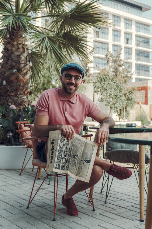 Smiling Man in Eyeglasses Sitting with Newspaper