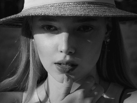 Black and white portrait of a woman wearing a sun hat with soft lighting.