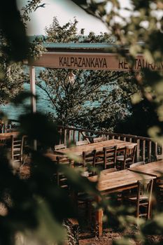 Charming seaside restaurant patio with wooden tables and chairs surrounded by greenery.