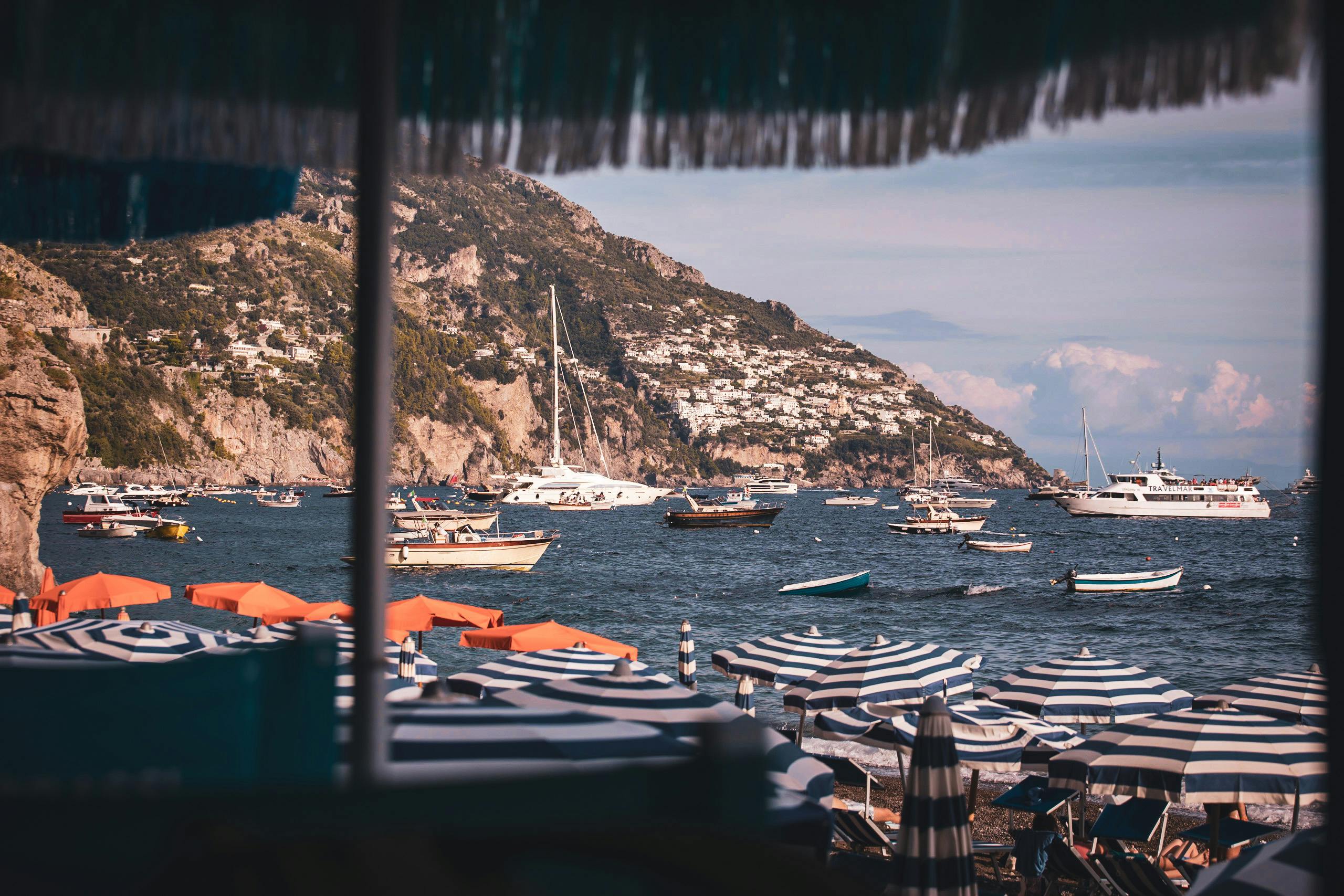 Charming seaside scene in Positano, Italy, featuring colorful boats and umbrellas.