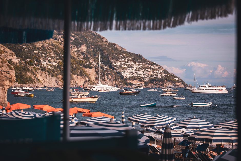 Charming seaside scene in Positano, Italy, featuring colorful boats and umbrellas.