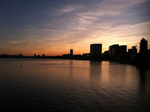 Silhouette Photograph of Buildings Near Calm Body of Water