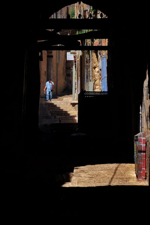 Free A narrow alleyway with shadows and a lone person climbing stone steps, creating a mysterious urban feel. Stock Photo