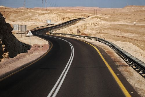 Free A scenic highway curves through the barren desert landscape on a sunny day. Stock Photo