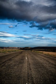 Open road stretching through a rural landscape under a dynamic sky, ideal for travel themes.