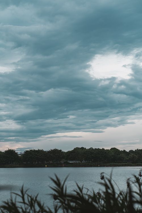 Free A tranquil scene of a cloudy sky reflecting over a peaceful lake at dawn. Stock Photo