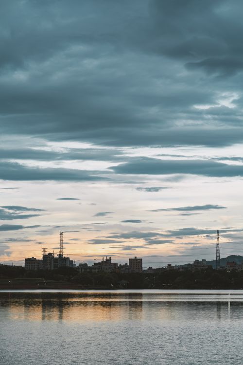 Free Beautiful cityscape reflection at twilight with dramatic clouds and a tranquil waterfront. Stock Photo