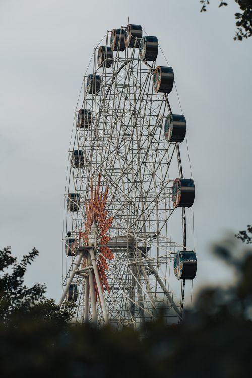 Free A towering Ferris wheel stands out against a cloudy sky at a theme park. Stock Photo