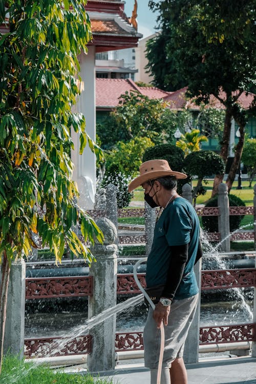 A man in a straw hat is watering a fountain