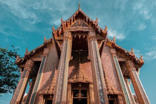 Free A beautiful Thai temple with intricate designs and vibrant colors against a clear blue sky. Stock Photo