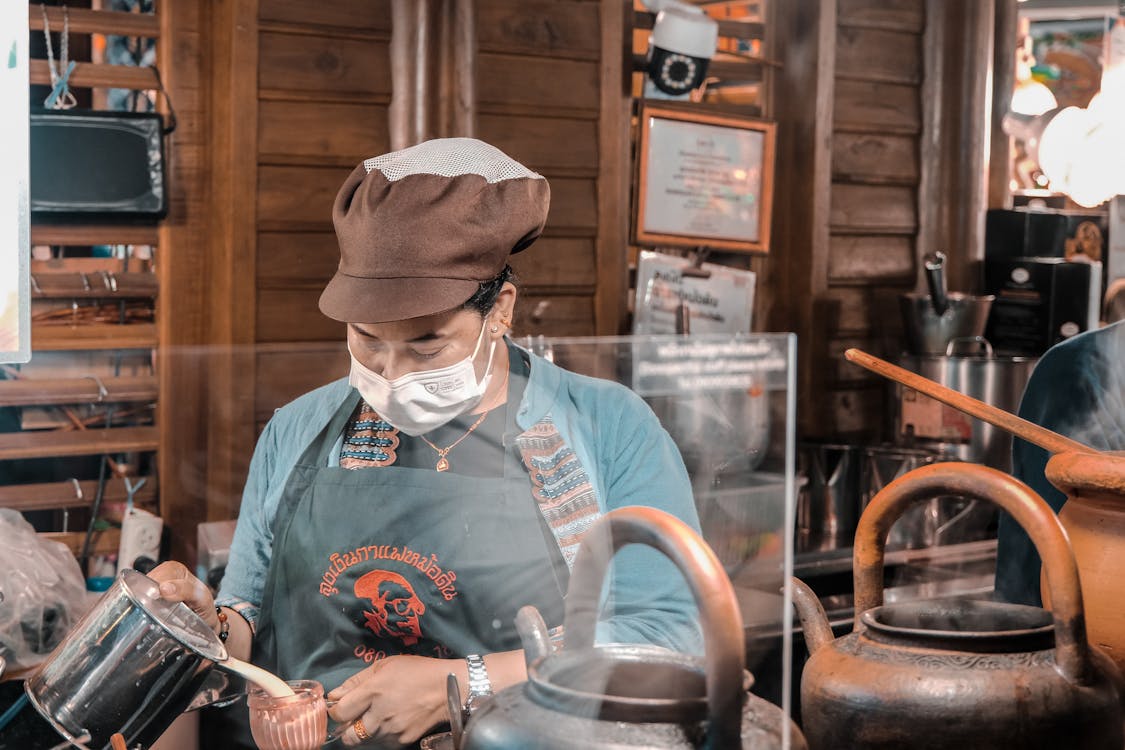 A woman in a face mask is preparing tea