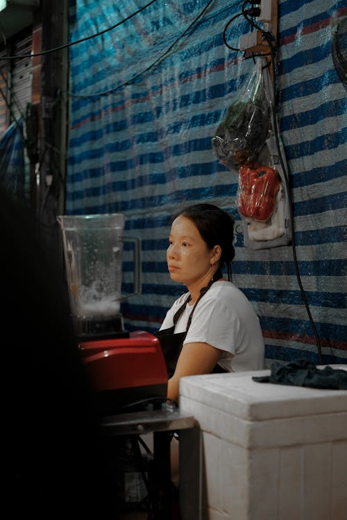 A woman sitting at a table in front of a food stand