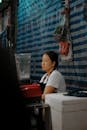 A thoughtful Asian woman at a street market stall in Bangkok, Thailand.