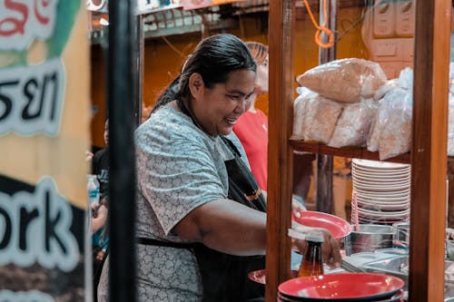 A woman in an apron serving food at a market