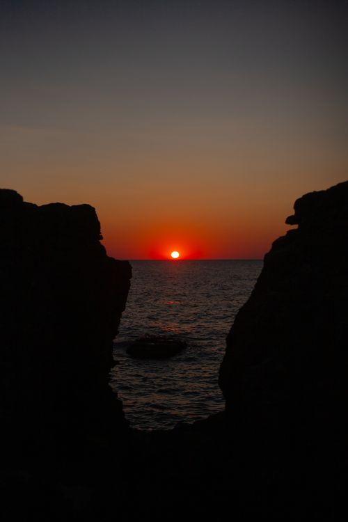 Free Beautiful sunset view between rocky cliffs by the sea. Ideal for nature and travel themes. Stock Photo