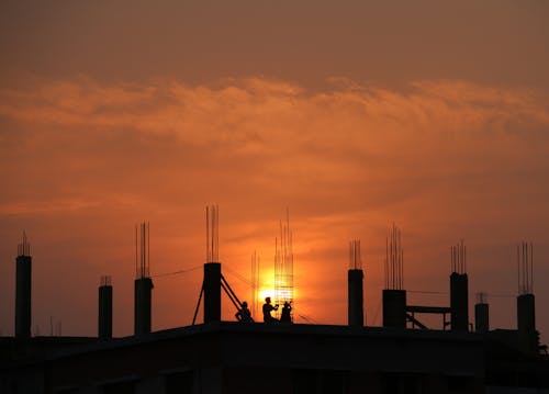 Schattenbild Der Männer Auf Der Baustelle Während Des Sonnenuntergangs