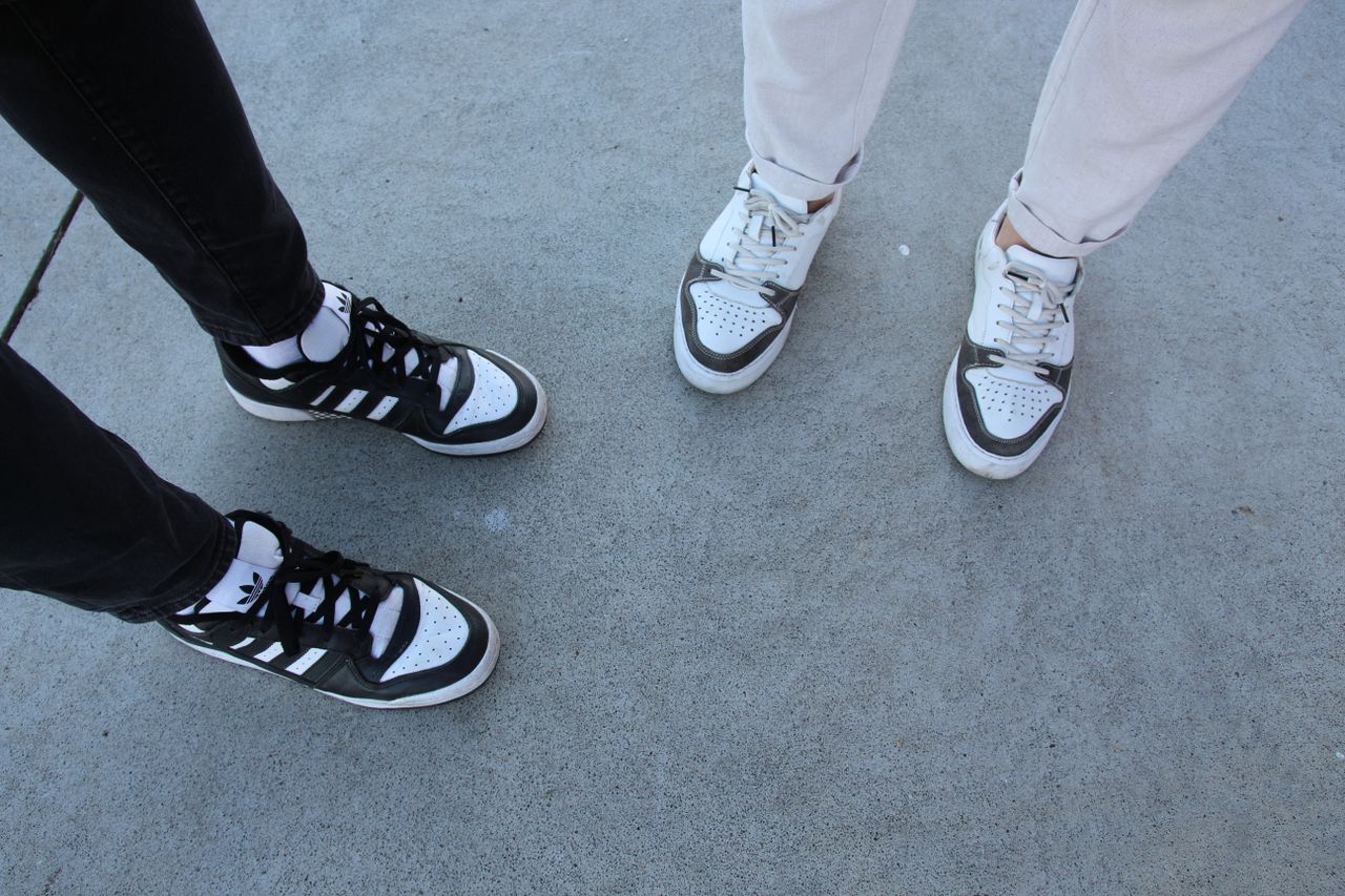 stylish close up of two people wearing trendy sneakers on a concrete p