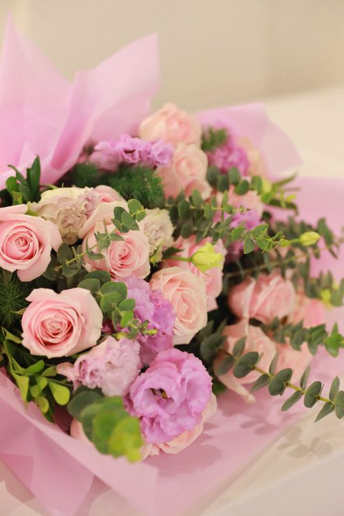 Free Exquisite bouquet with pink and purple flowers wrapped in pastel paper, perfect for gifting. Stock Photo