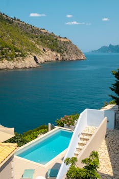 Experience the serene beauty of a Greek island coast with an infinity pool overlooking the sea.