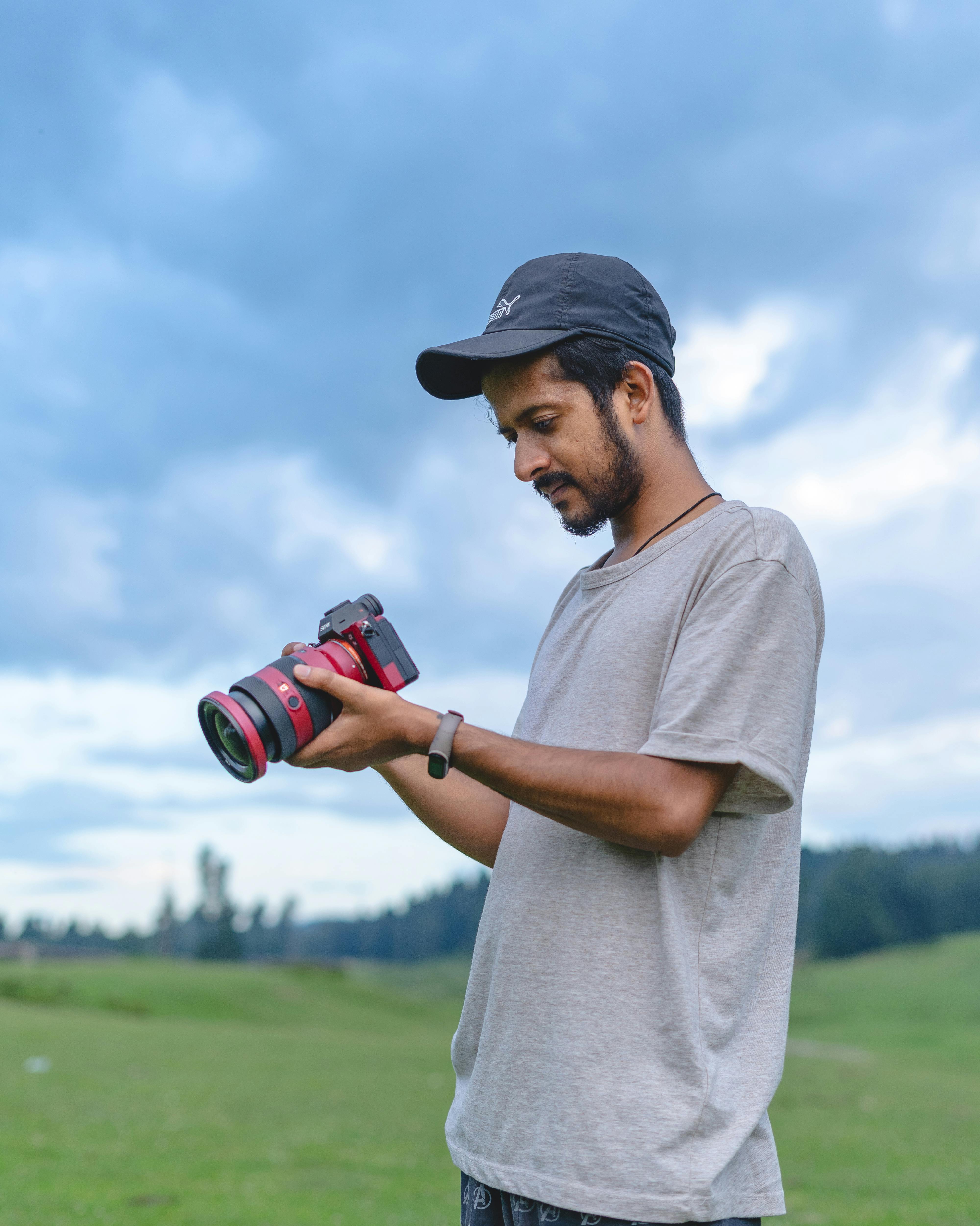 Man in casual wear inspecting camera in scenic Badgam outdoors.