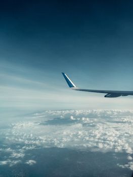Beautiful view of an airplane wing with fluffy clouds and blue sky from the window. Ideal for travel themes.