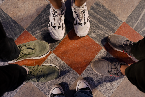 Free Four pairs of sneakers on a patterned floor, viewed from above. Stock Photo