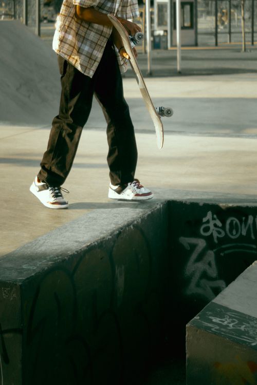 Free A skateboarder holding his board while navigating an urban skatepark. Stock Photo