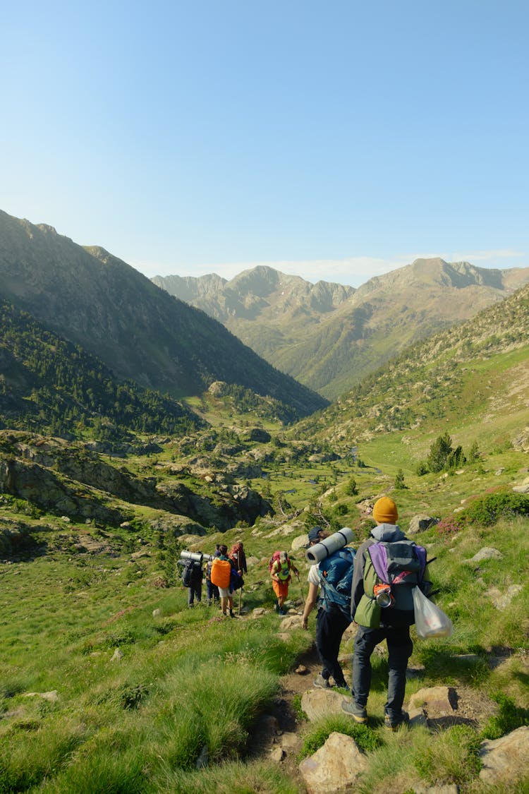 People Hiking In Valley In Mountains