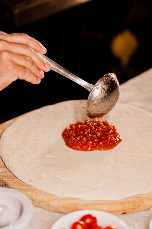 Putting Tomato Sauce on Dough for Pizza