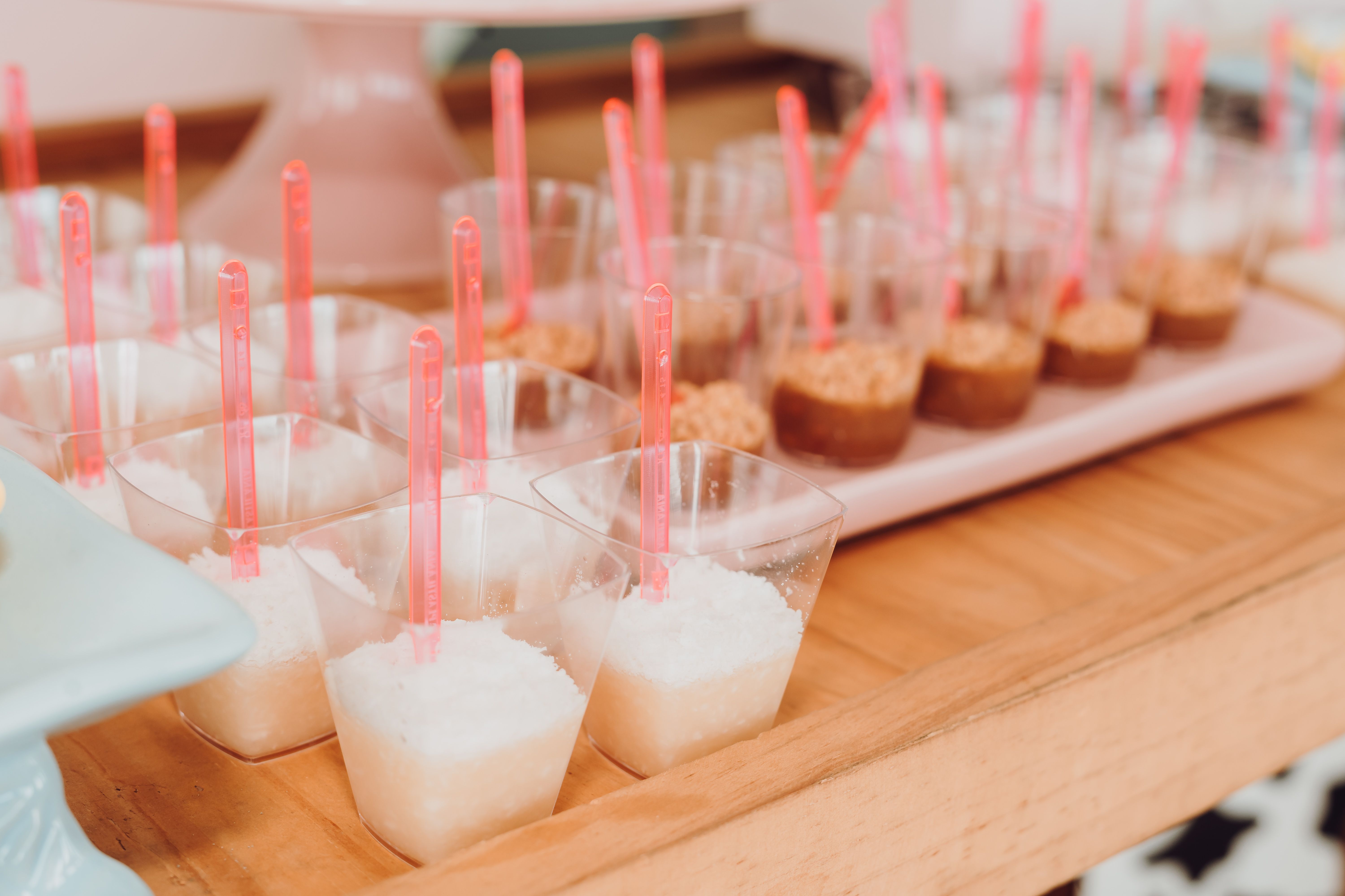 Array of mini desserts in transparent cups with pink spoons, perfect for catering events.