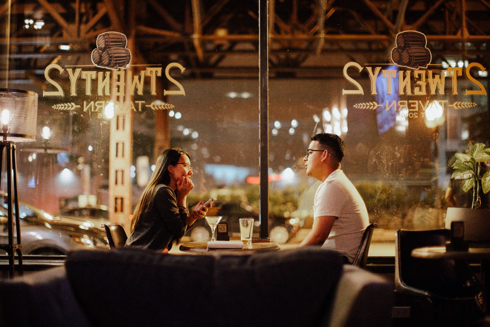 Two people talking across drinks in a bar, the kind of scene no recommendation engine can fully rehearse.
