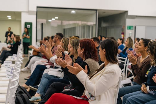 A diverse group of adults clapping during a professional indoor meeting.