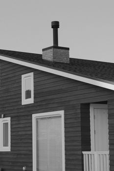 Close-up of a modern wooden house with a chimney captured in black and white.