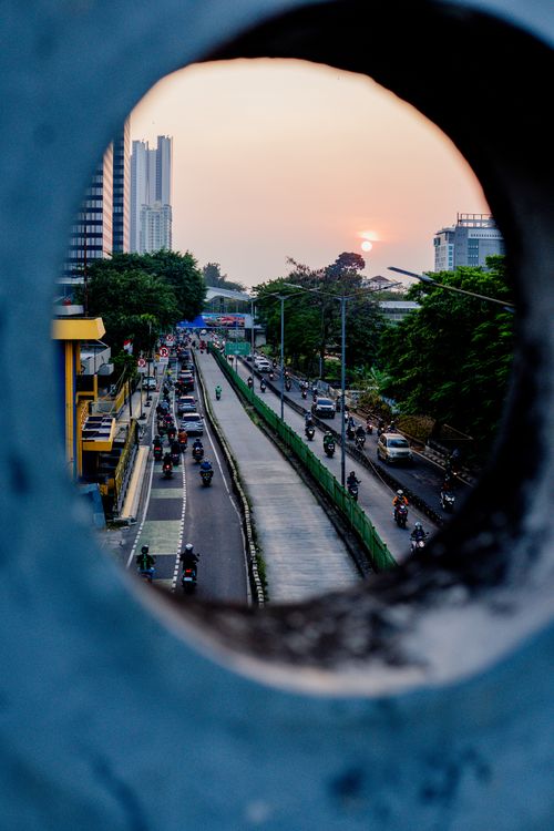 Free A vibrant city street scene captured through a circular structure during sunrise. Stock Photo