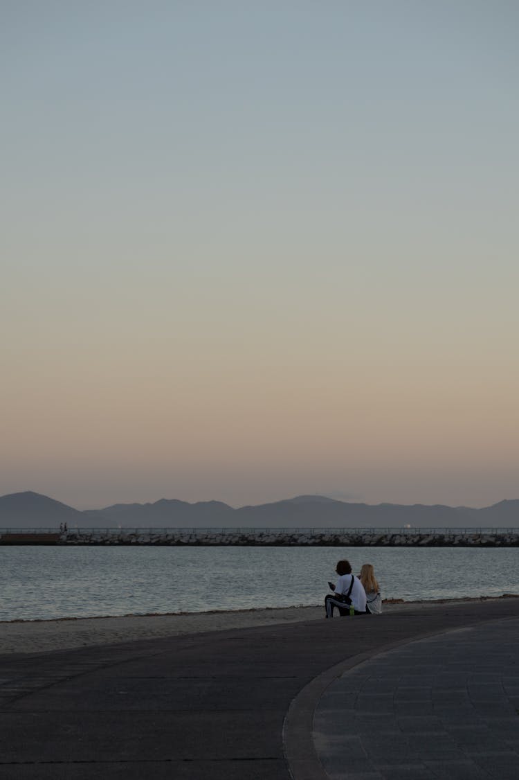 Couple Sitting On The Beach At Dusk