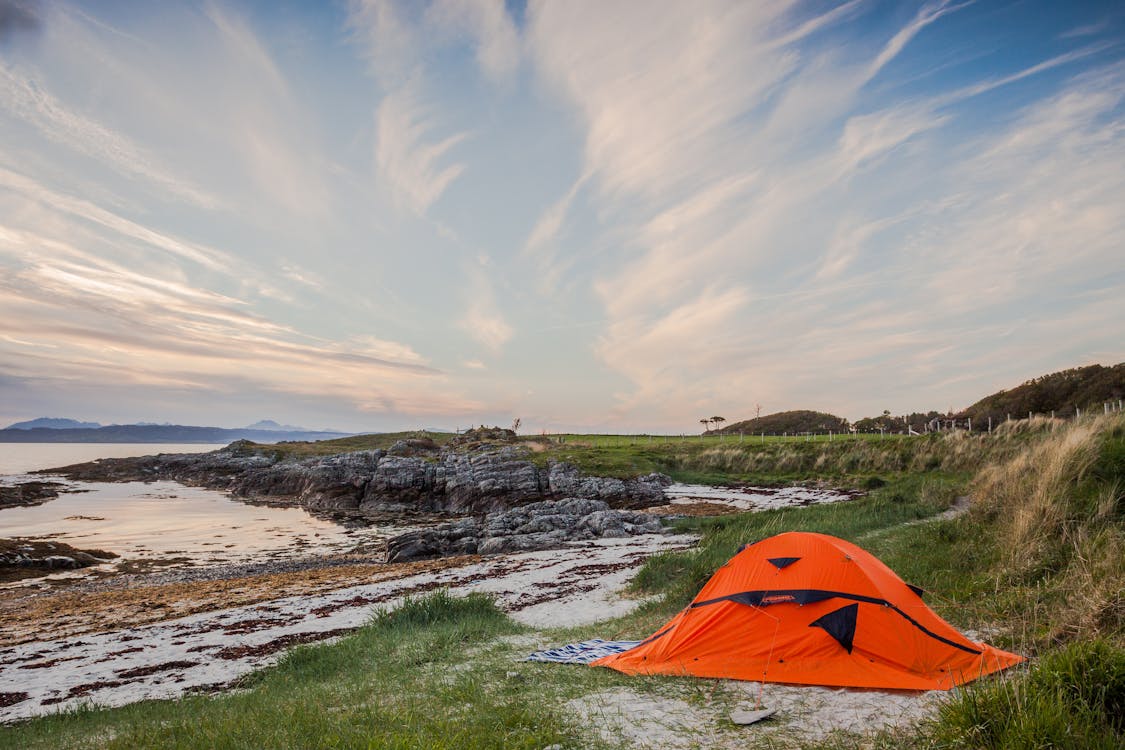 免費 白天在水體附近的橙色露營帳篷 圖庫相片