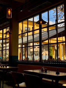 Warm and inviting café interior featuring large windows and wooden furniture, ideal for urban relaxation.