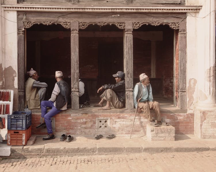 Group Of Men Sitting At A Building Porch