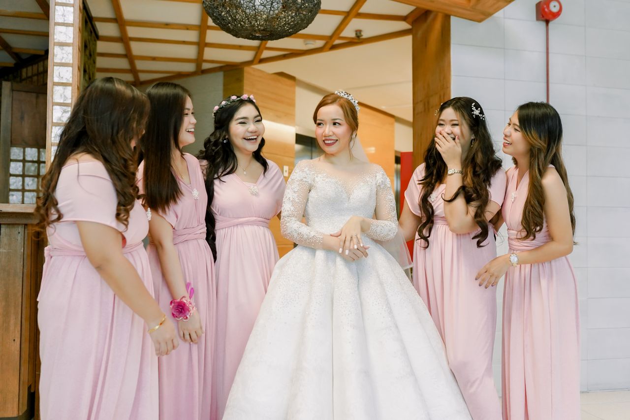 Bride surrounded by bridesmaids in soft pink dresses