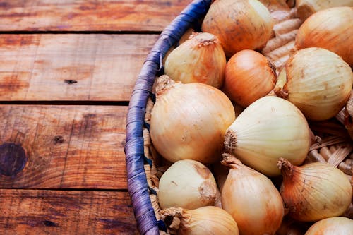 Onions in a basket on a wooden table