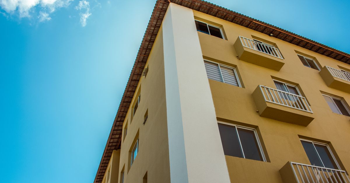 Close-up of a yellow residential building facade against a clear blue sky.
