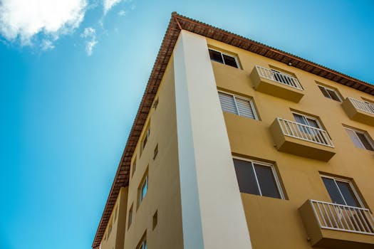 Close-up of a yellow residential building facade against a clear blue sky.